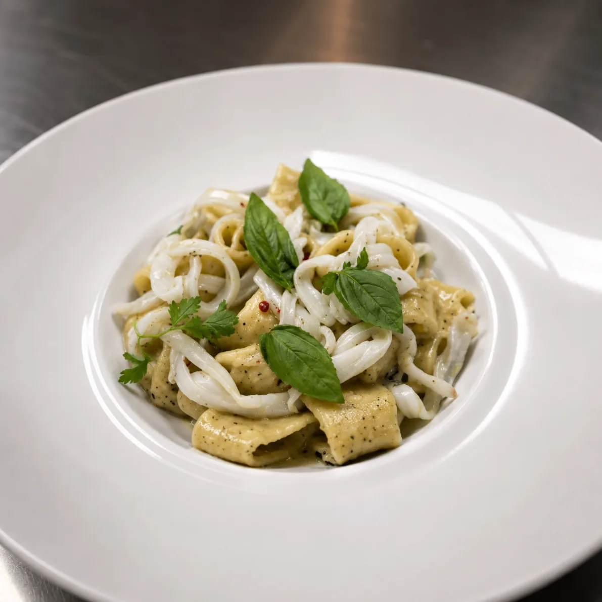 Handmade pasta with calamari and basil in creamy pepper sauce