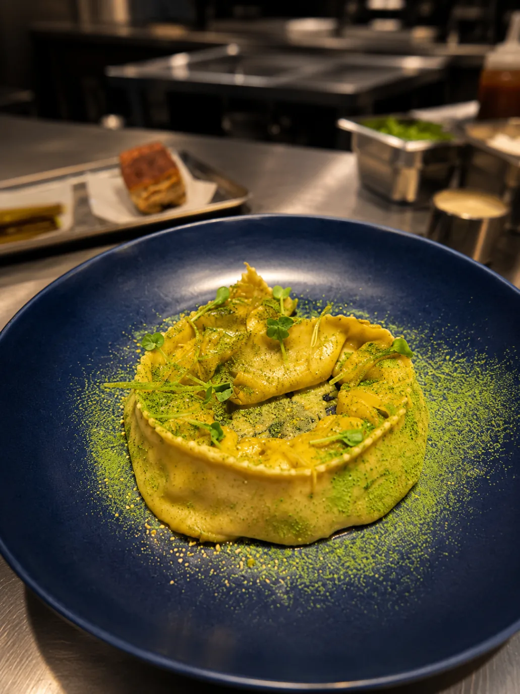 Ravioli with pistachio dust and micro herbs on navy plate