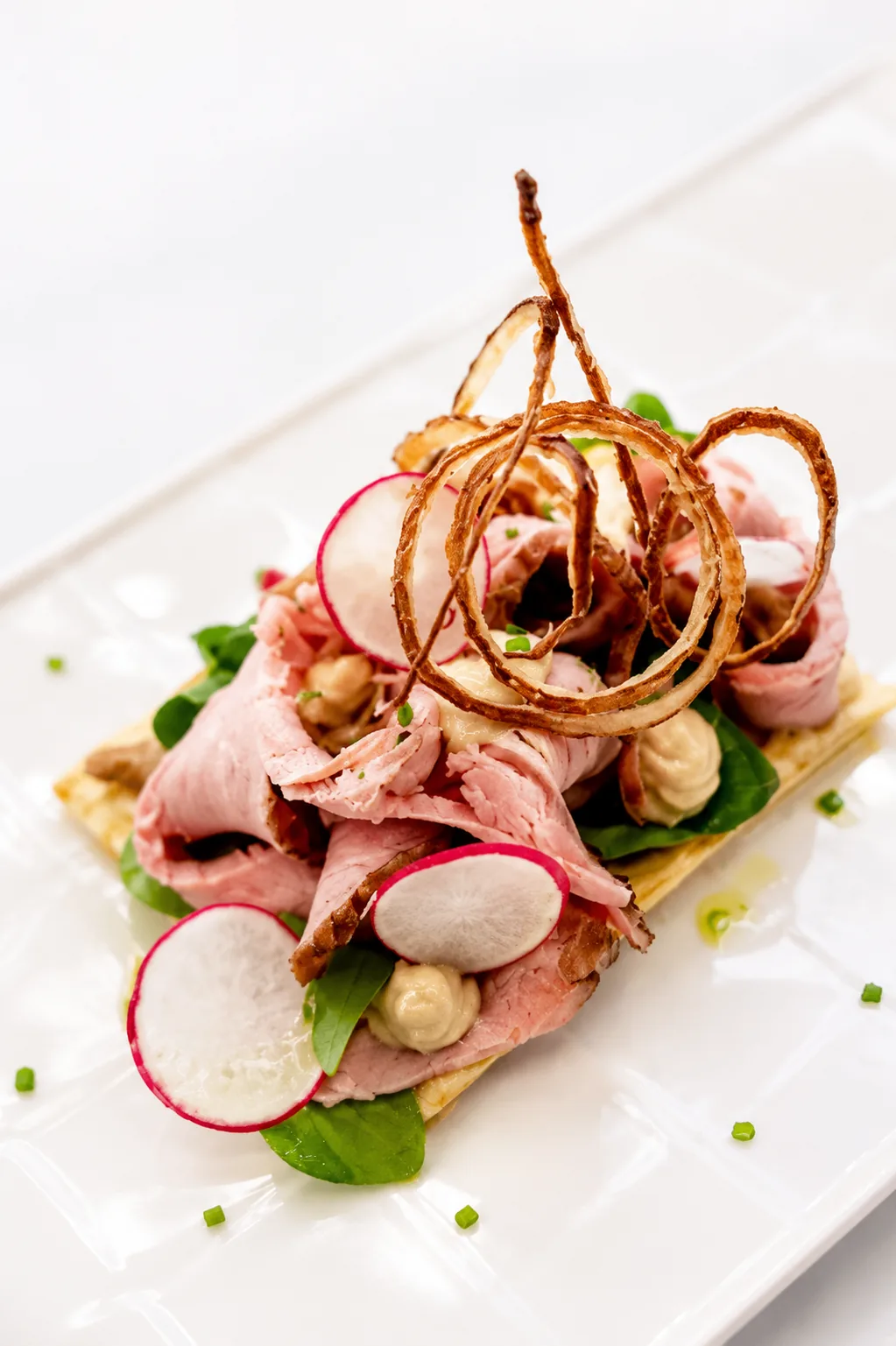 Open-faced roast veal canapé with radish and crisp onions